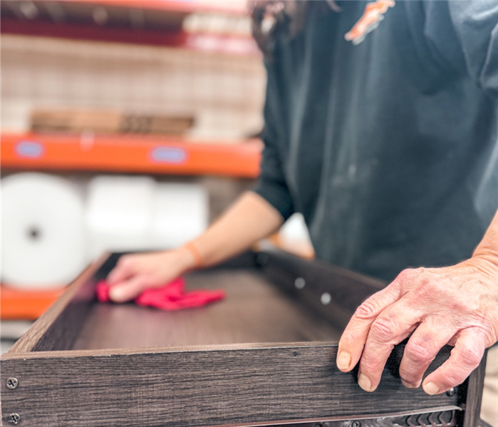 SERVPRO technician cleaning a wooden drawer, highlighting our expertise in restoring damaged items.